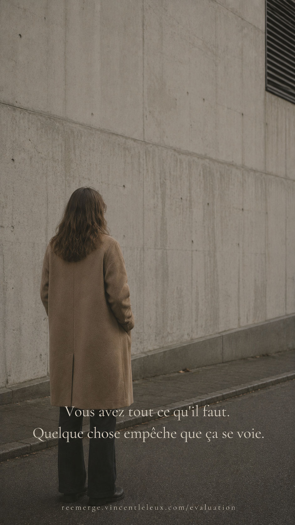Woman in camel coat standing near a concrete wall, Re-Emerge